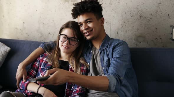 Cute Happy Couple of Young Hipsters Smiling and Cuddling on the Couch While Trying to Find a Perfect alt