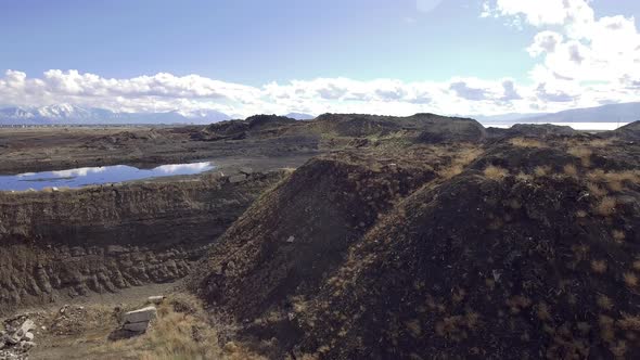 An aerial drone shot flying past the catch pond and slag heap from the former Geneva Steel mill. alt