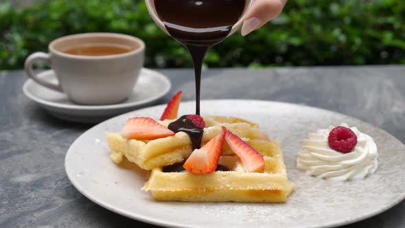 Woman Hand Pouring Chocolate Syrup on American Buttermilk Pancakes alt