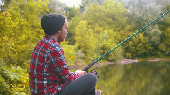 Young Man Sitting on Fishing - Pulling the Rod and Spinning the Roulette alt