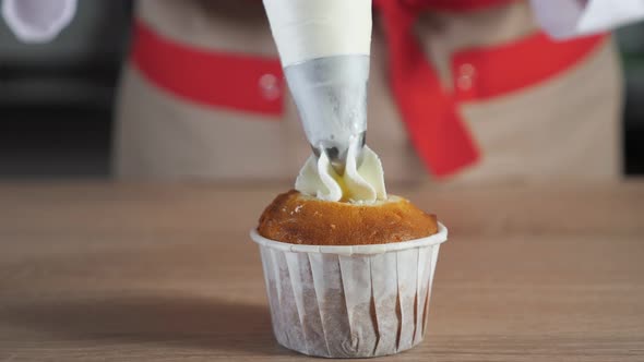 Pastry Chef Decorates Muffin in Paper Cups White Cream with Pastry Bag alt