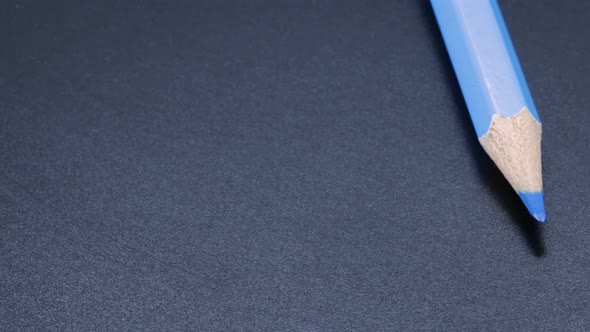 Clear blue colored pencil crayon rotating macro shot, zoom close up video. Black background. alt