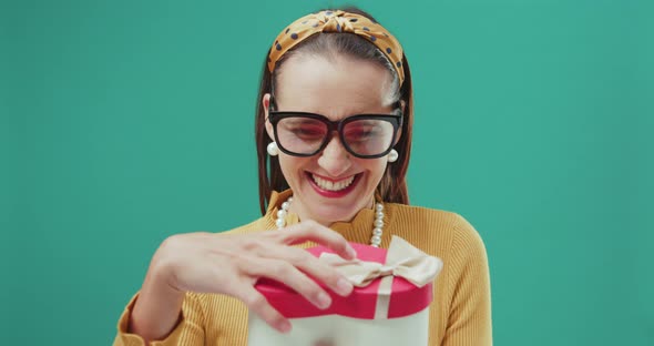 Woman opening a heart-shaped gift box and looking very happy. Isolated.