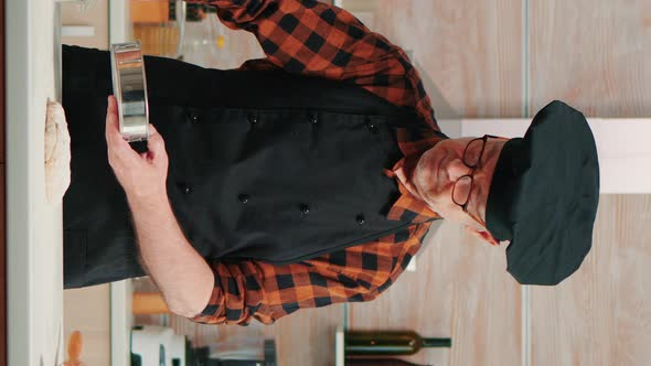 Vertical Video: Baker with Bonete and Kitchen Apron Using Metallic Sieve alt