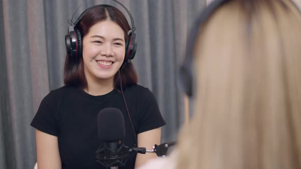 Two Young Asian women podcaster conversations while recording podcasts.