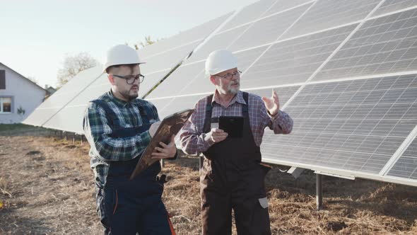 Two Engineers Controling Alternative Solar Batteries on a Factory alt