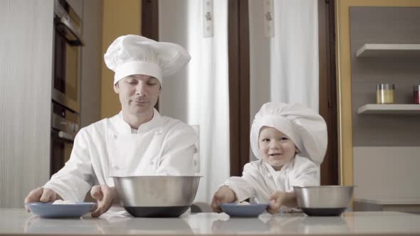 Dad and Son Sprinkle Flour in a Bowl for Making a Cake