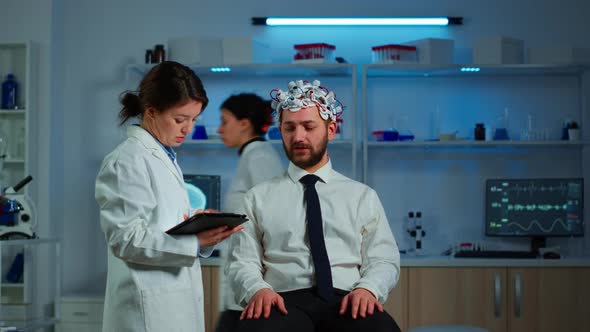 Patient Wearing Brainwave Scanning Headset Discussing with Neurological Researcher alt