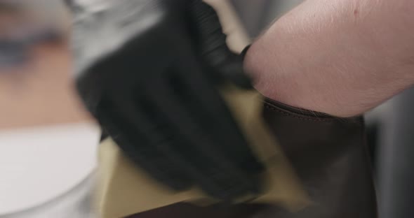 Slow Motion Man Hands in Black Gloves Polishing Brown Leather Chukka Boots with Cloth alt