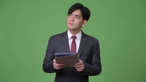 Young Handsome Asian Businessman Using Digital Tablet alt