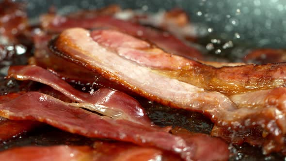 Super Slow Motion Shot of Roasted Bacon Slices Falling Into Pan at 1000 Fps alt