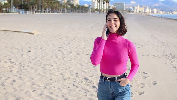 Young Woman Calls on the Phone and Walks Along the Sea