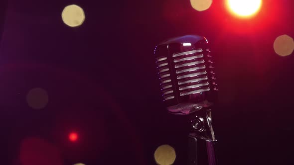 Vintage Microphone Against Dark Blurry Background with Bright Flashing Lights alt