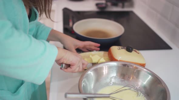 a Woman Cuts Off a Piece of Butter and Puts It on a Frying Pan to Fry an Omelet alt