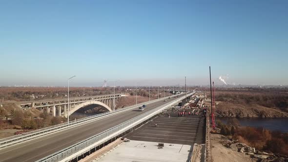 Construction of a bridge across the river. Automobile traffic on the bridge. View from the top. alt
