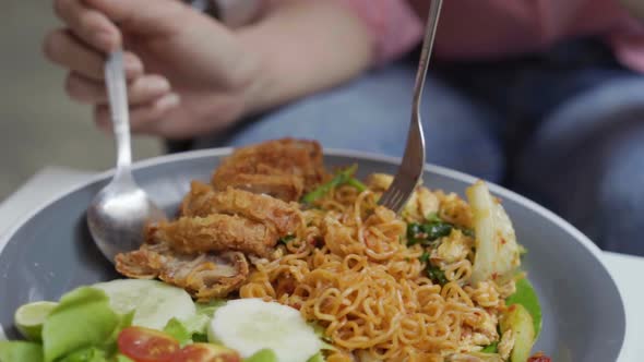 slow-motion of hand using fork for eating instant noodle