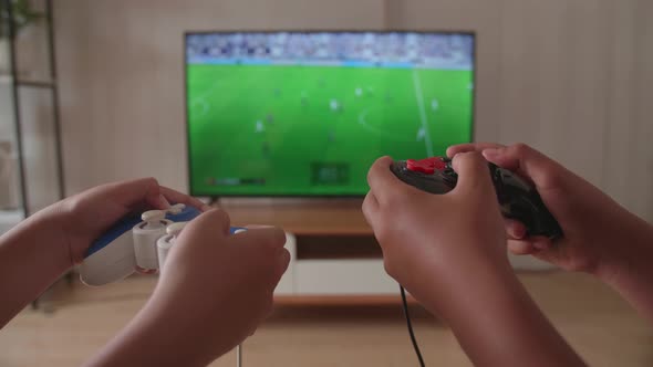 Close Up Children's Hands Holding Joystick Game Play Soccer Video Game On Tv alt