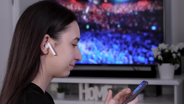 Young Woman with Wireless Earbuds Using Smartphone