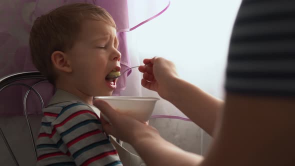 Food Nutrition Childhood Concepts  Medium Shot Mom Feeding Infant Kid Boy with Rubber Spoon