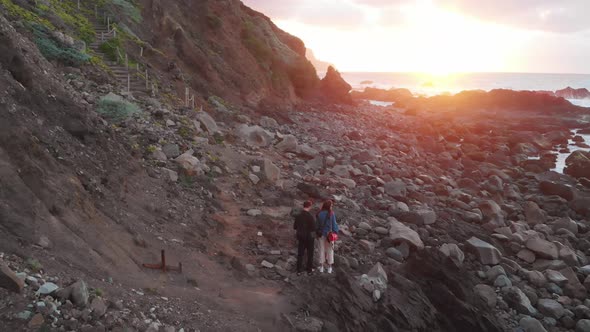 The Guy and the Girl Stand on the Ocean at Sunset, at the Foot of the Cliffs, Benijo Beach, Tenerife alt