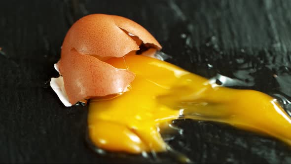 Super Slow Motion Shot of Falling and Breaking Whole Egg on Black Table at 1000 Fps. alt