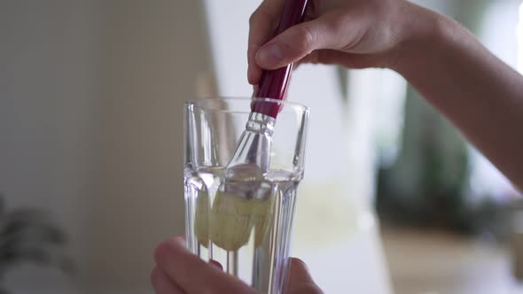 The Artist Moisturizes the Brush in a Glass of Water
