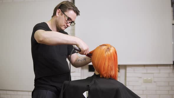 Closeup Shot of a Woman Having Her Hair Straightened By a Male Professional Hair Stylist in Hair alt