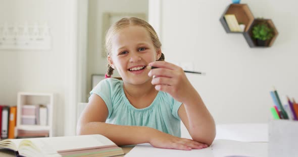 Portrait of caucasian girl holding a pencil smiling looking at the camera at home alt