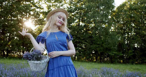 Female with Wicker Basket Stay in Blooming Lavender Field on Summer Day with Bouquet Lavender in a alt