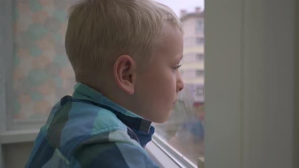 Boy Looking Out the Window Waiting for Parents at Home Alone