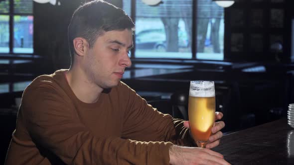 Young Man Smiling To the Camera After Sipping Delicious Beer From a Glass alt