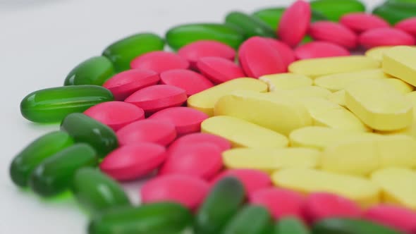 Close shot of yellow,pink and green tablets placed in a circle view alt