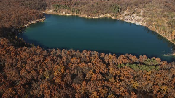 High Above Drone View on Clear Turquoise Blue Colored Lake and Beautiful Autumn Forest