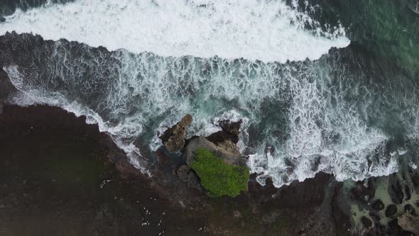 Top down aerial view of giant ocean waves crashing and foaming in coral beach alt