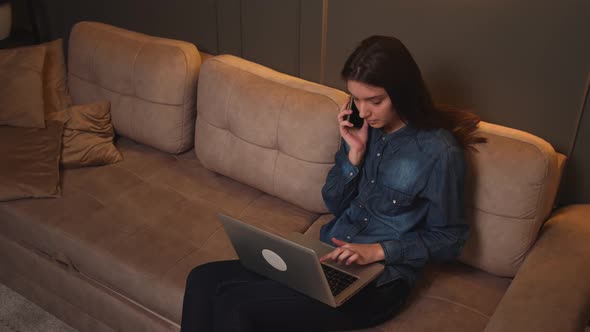 Focused Businesswoman Talking on a Mobile Phone While Working on a Laptop alt