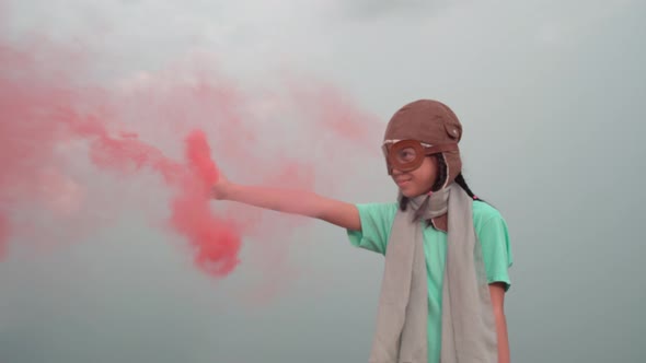 Young girl with pilot goggles and hat, Asian kid playing at outdoor with color smoke