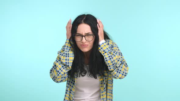 Beautiful Brunette Woman in Glasses and Casual Clothes Cover Ears and Bend Down From Annoying Loud alt
