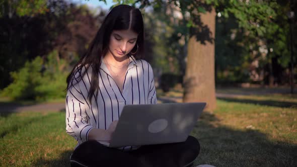 Attractive Woman Freelancer Working Using Laptop Outdoor in Park on Grass