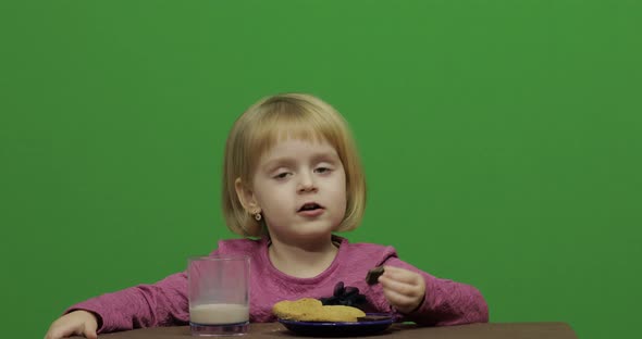 Girl Sitting at the Table and Eating Chocolate, Cookies and Drinks Cacao alt
