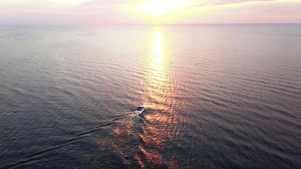 Aerial Sunset Shot of Yacht Sailing During Sunset with Red and Orange Sky Above Reflecting Sea alt