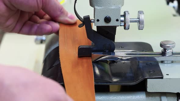 Man Using a Machine To Frame the Edge of a Leather Piece of Material. Close Up View. Craft and alt