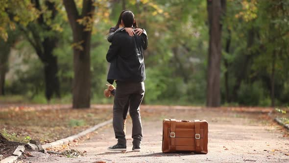 young coupe with suitcase kissing in the autumn par