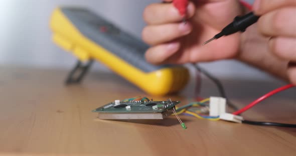 Technician Testing The Circuit Board With A Multimeter And Measuring The Signal