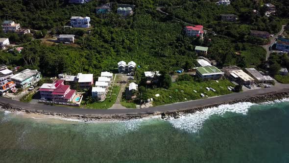 Aerial approach over water to local homes on a beach BVI island Tortola. alt