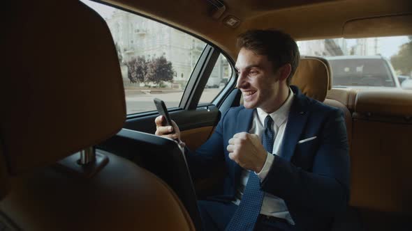 Excited Business Man Recording Motivating Video on Mobile Phone in Business Car alt