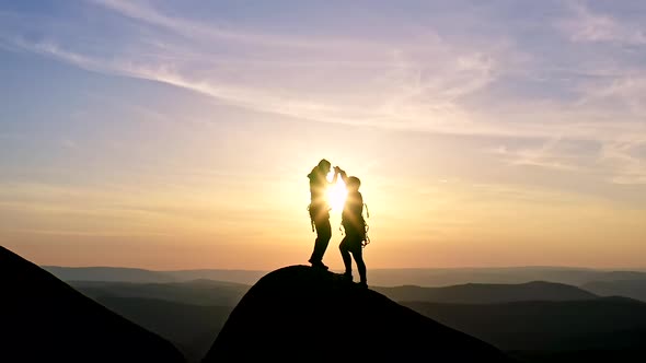 Slow Motion of a Man and a Woman Victoriously Shake Hands and Embrace Standing on a Mountaintop at
