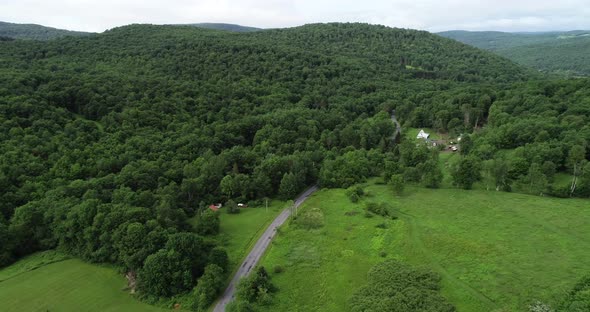 A car drives on a road into the beautiful scenery of the Catskill Mountains in New York. alt