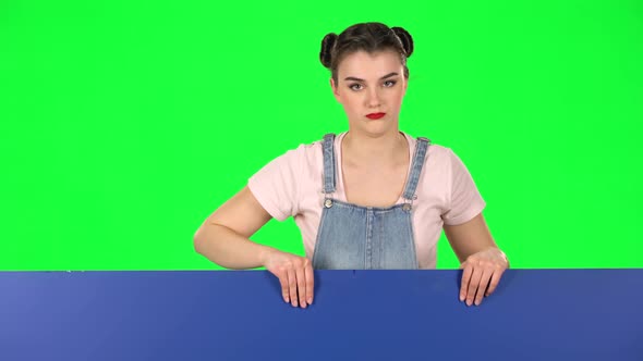 Girl Looking Out From Behind Blue Blank Placard Looks at Him and Shakes His Head Disapprovingly alt