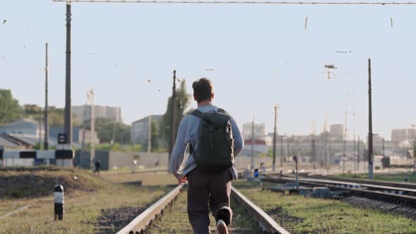 Happy Man Runs Along Train Tracks and Smiles Raising His Hands Up alt
