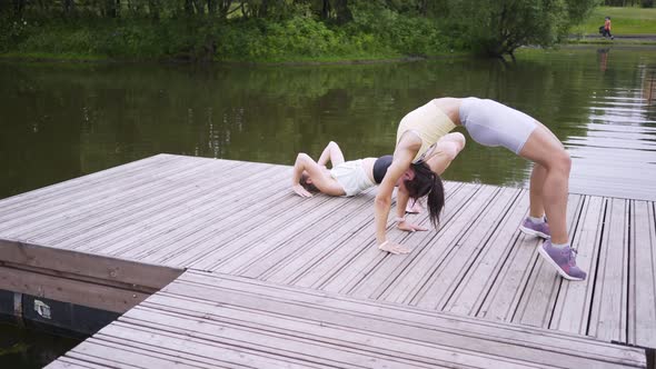 Sportswomen Do Exercises and Rest on Wooden Pier in Park